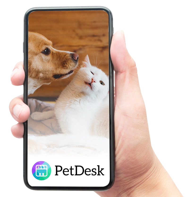 Hand holding a smartphone displaying the PetDesk app with a dog and white cat on the screen.